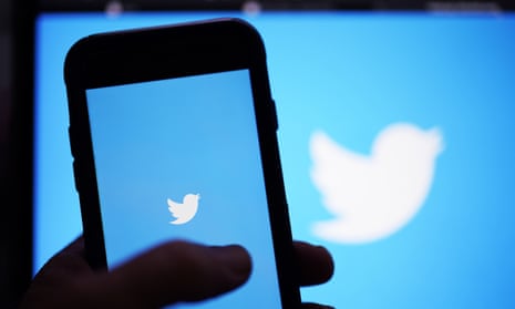 Twitter logo on a phone in front of a screen showing the Twitter logo