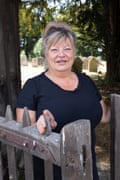 A smiling woman standing at a churchyard gate