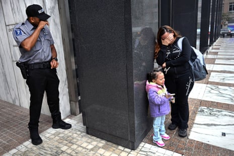 A security guard cries, watching a woman and her child weep after her husband was detained by ICE in New York city