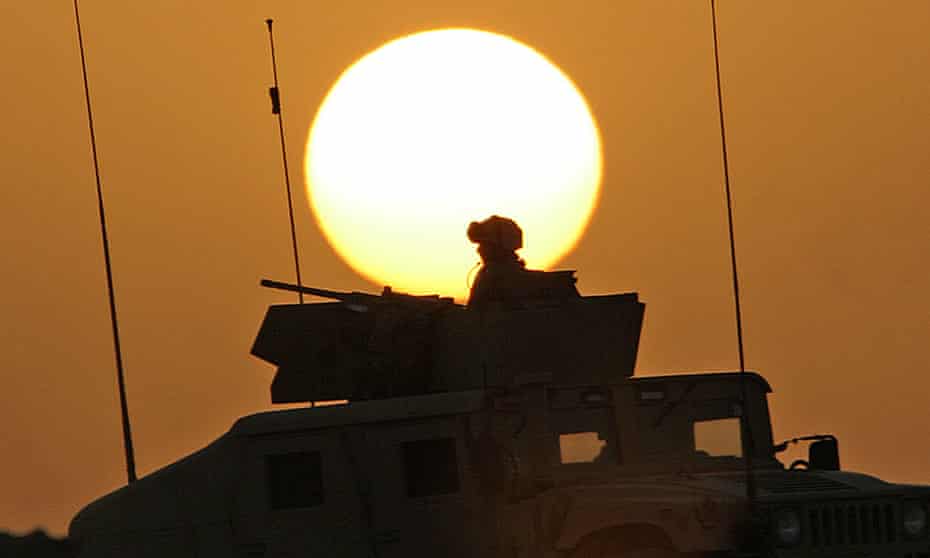 A US soldier sits atop a humvee at sunset in Iraq, 2006.