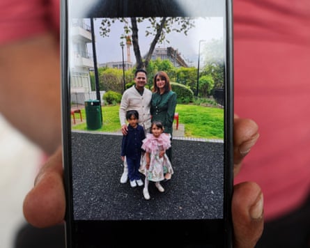 A family member holding a picture on a mobile phone of the Syed family.