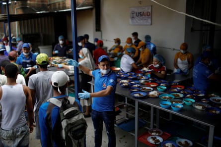 Volunteers and people queuing for food at a basic kitchen canteen in Colombia