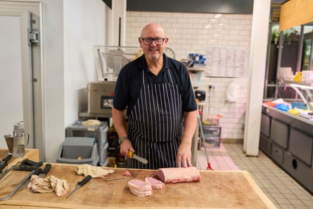 John Cross standing at a butcher's block with meat on top of it