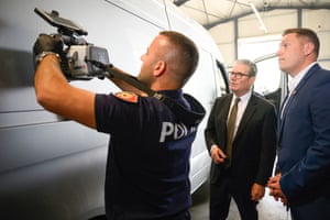 The UK prime minister, Keir Starmer, watches police officer with large camera