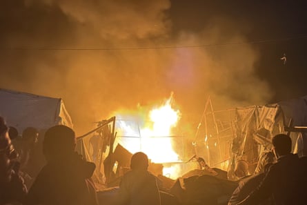 Tents on fire after an IDF strike with people milling around trying to extinguish fire
