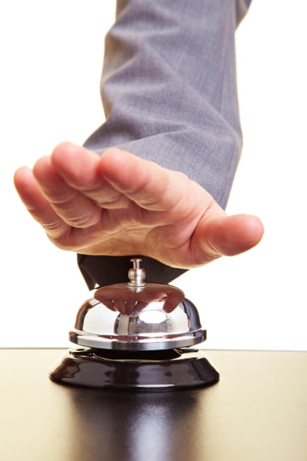 A hand pictured about to ring the hotel front desk bell