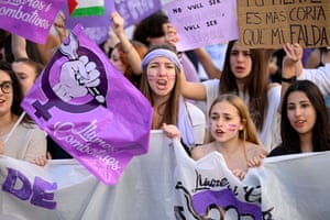 Students wearing white and purple hold signs on a demo