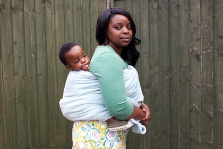 Woman with a baby strapped to her back, both facing the camera