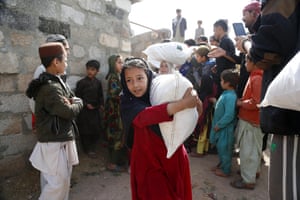 A girl carries away a large bag of donated goods as others wait to receive theirs