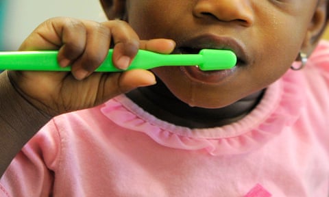 young child with toothbrush brushing her teeth 