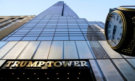 An image of a windowed skyscraper taken from the sidewalk all the way up to the sky, with a freestanding clock on the right, and the words 'Trump Tower' in gold above the entrance.