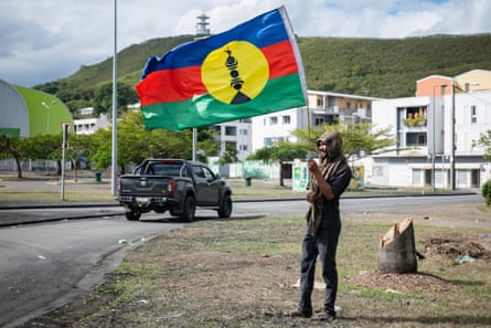 A pro-independence supporter waves a flag on the side of a road ahead of legislative elections in Nouméa inJune 2024.
