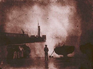 Newhaven Harbour with the paddle steamer, Stirling, moored by the pier, modern print from the original negative, taken 1843-6One of the problems with early photography was taking pictures of the land without the much brighter sky overdeveloping and blanking out. Hill and Adamson worked with light bounced from the water. This picture, taken at full-tide and possibly after rain has washed the quayside, has become too dark for the detail, but the reflection of the man looking out, and the boat perched on the line of the quay, add to the shape of the paddle steamer to make it a satisfactory image
