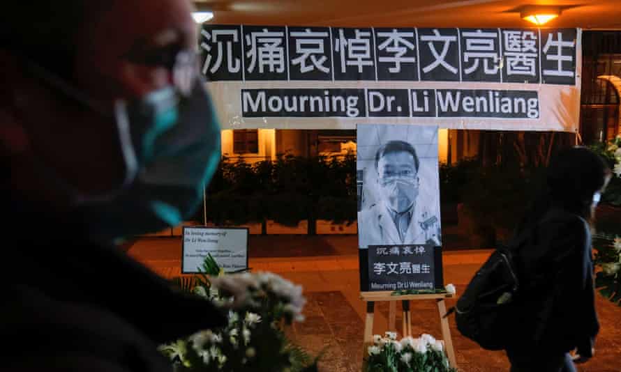 People wearing masks attend a vigil for Li Wenliang, an ophthalmologist who died of coronavirus at a hospital in Wuhan.