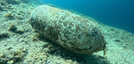 A rusting shell covered in barnacles on the sea floor