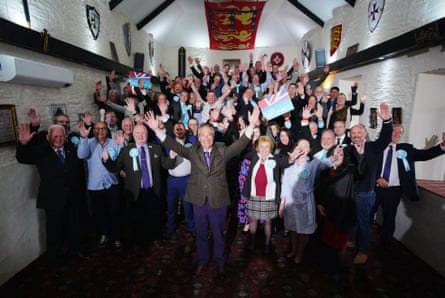 Farage stands at the front of a group of people with their arms raised