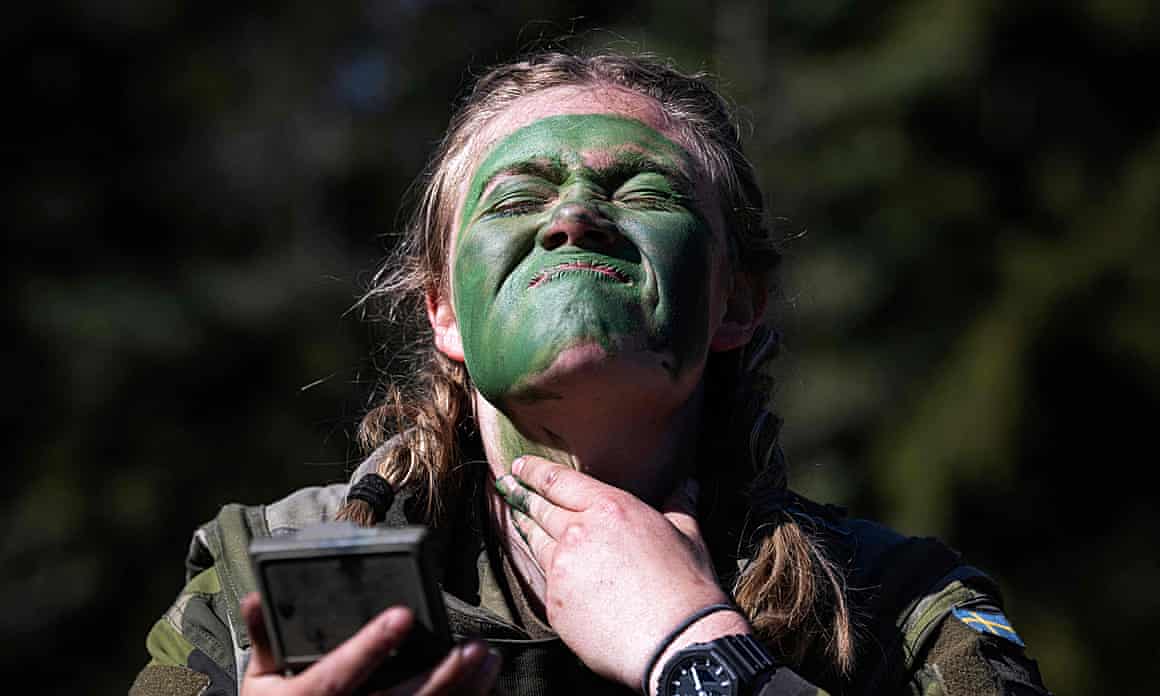 A soldier of the P18 Gotland Regiment covers her face with green paint