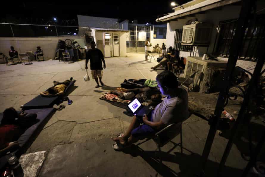 A Cuban man looks at a computer screen while others rest around the patio at El Buen Pastor shelter for migrants in Cuidad Juárez, Mexico.