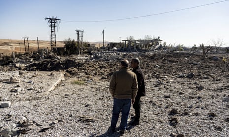 People look at a site damaged by Turkish airstrikes in Hasakah province, Syria.