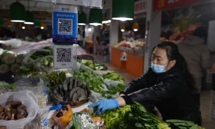 A vendor works behind QR payment codes at a market in Beijing.