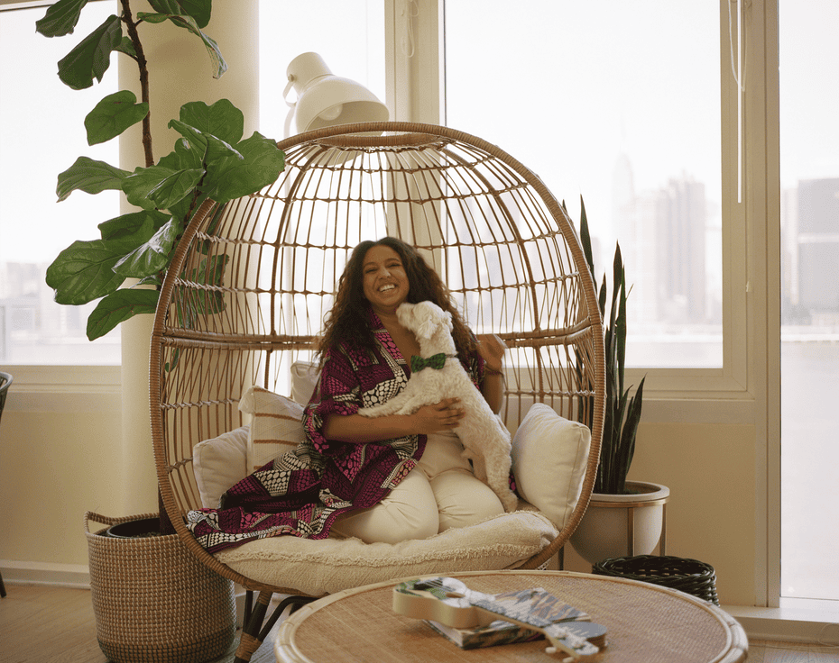 A woman in a rattan chair plays with her small white dog