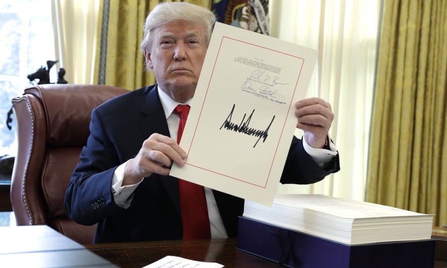 Donald Trump displays the $1.5tn tax cut he had just signed, on 22 December 2017.