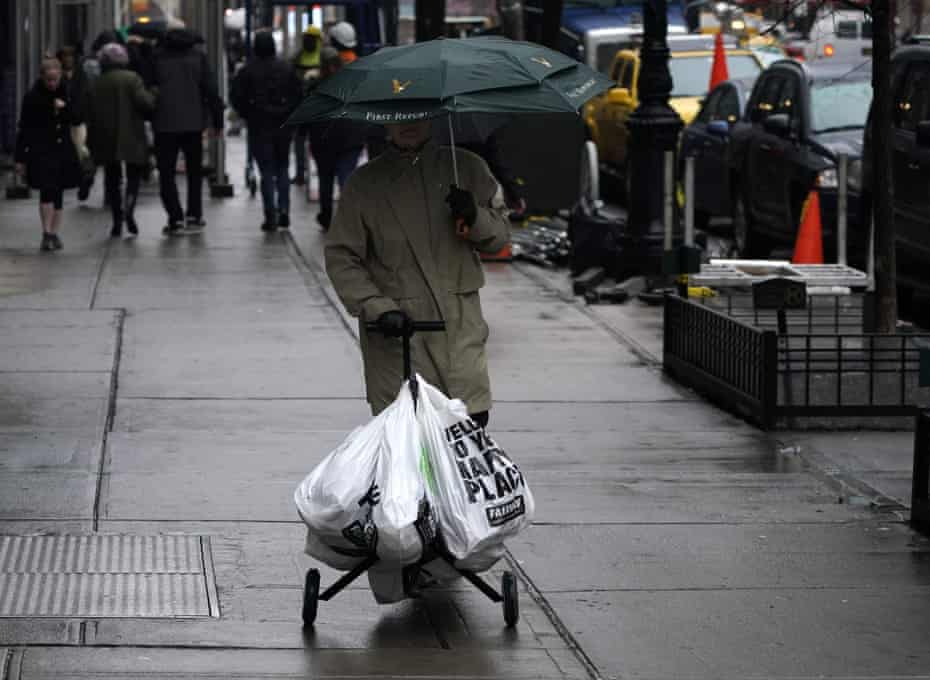 A person with groceries in plastic bags walks on the Upper East Side in New York on 28 February 2020