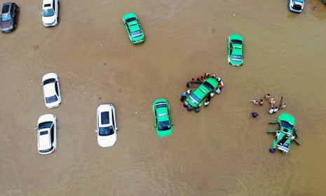 People push a stranded taxi after a heavy rain in Lanzhou