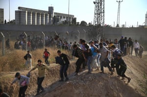 Syrian refugees run into Turkey after breaking the border fence at Akcakale in south-eastern Turkey on Sunday 14 June 2015. 