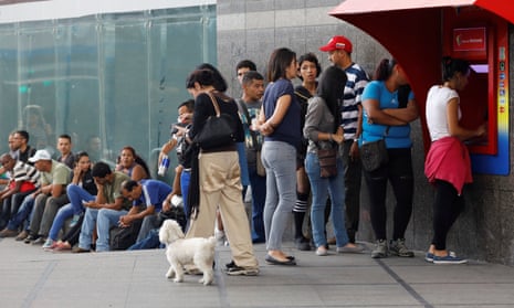 People line up to withdraw cash from an ATM outside a Banco de Venezuela in Caracas.