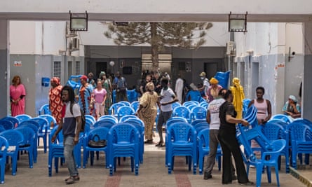 African people setting up blue plastic chairs in a courtyard for a film show. 