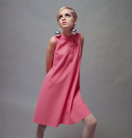 British model Twiggy in a pale pink mini dress and large bauble earrings, December 1966