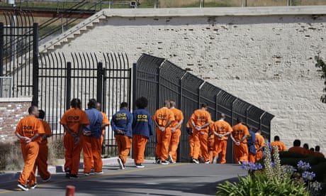 inmates walking single file along a fence
