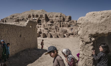 Afghan children play in front of caves where they live at the old city of Bamiyan in Afghanistan
