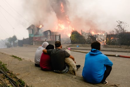 Members of a family watch as their home burns to the ground in Penco, Chile, 18 January 2026