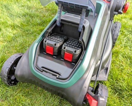 The Bosch Rotak lawnmower in the garden with the battery case open.