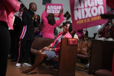 a woman sits in a pew as people hold signs in support of her