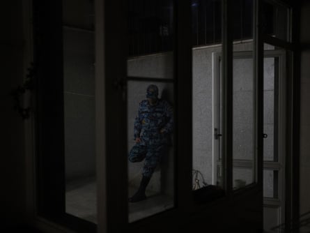 A fuzzy image of an unidentified man in military fatigues in the shadows.