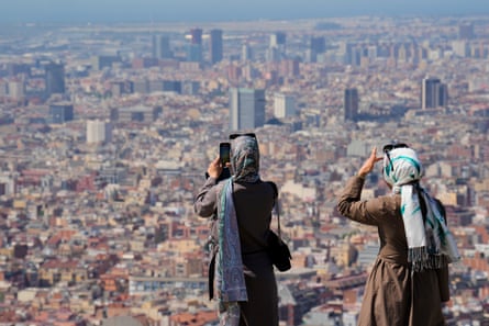 Tourists take photos of the city at Turo de la Rovira in Barcelona.