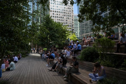 People sit on benches in the shade in Canary Wharf