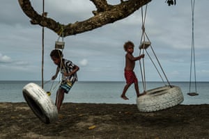 Children play with swings on an uprooted tree along a beach in Mele, that was once lined with vegetation, now largely lost to storms, erosion and other environmental pressures