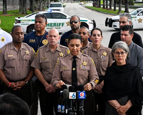 a sheriff speaks into a microphone in front of her colleagues