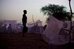 A young boy stands by the mosquito net that forms his family’s only shelter at night