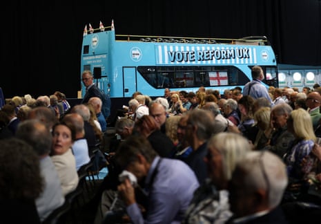 Supporters stand near a blue bus with the message 'vote Reform UK' at the conference.