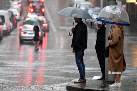 Members of the public shelter under the rain under umbrellas in Sydney