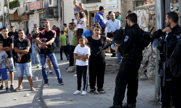 Palestinians look on as Israeli police set up a checkpoint in the east Jerusalem neighbourhood of Ras al-Amud.