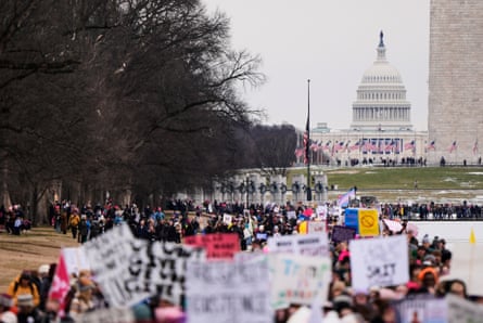 crowd of people holding signs with white building in the background