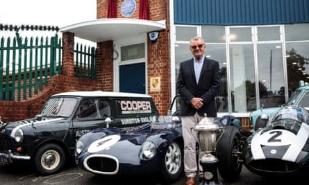 Mike Cooper, son of carmaker John Cooper, poses with historic cars at the former Cooper Car Company works, newly adorned with a blue plaque.