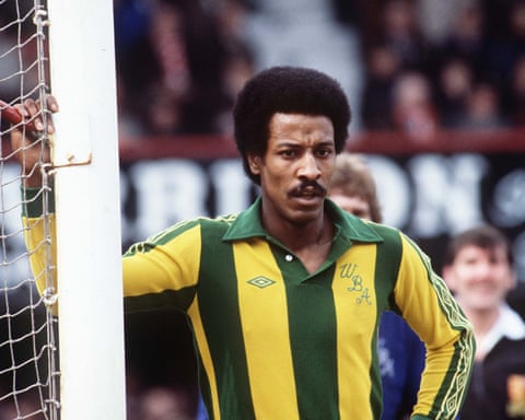 Brendon Batson standing next to a goalpost wearing a yellow and green striped football shirt.