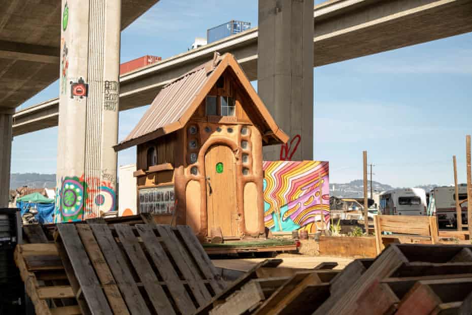 A model ‘cobin’, built for long-term living, overlooks materials used to build new ones under the Interstate 880 overhang.